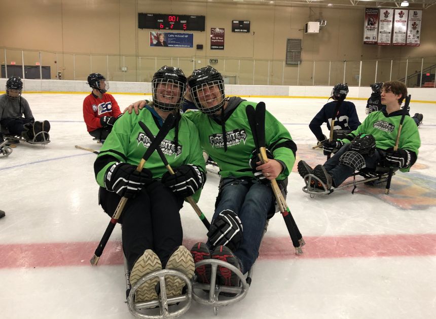 Smiling teammates on the ice during a para ice hockey game.